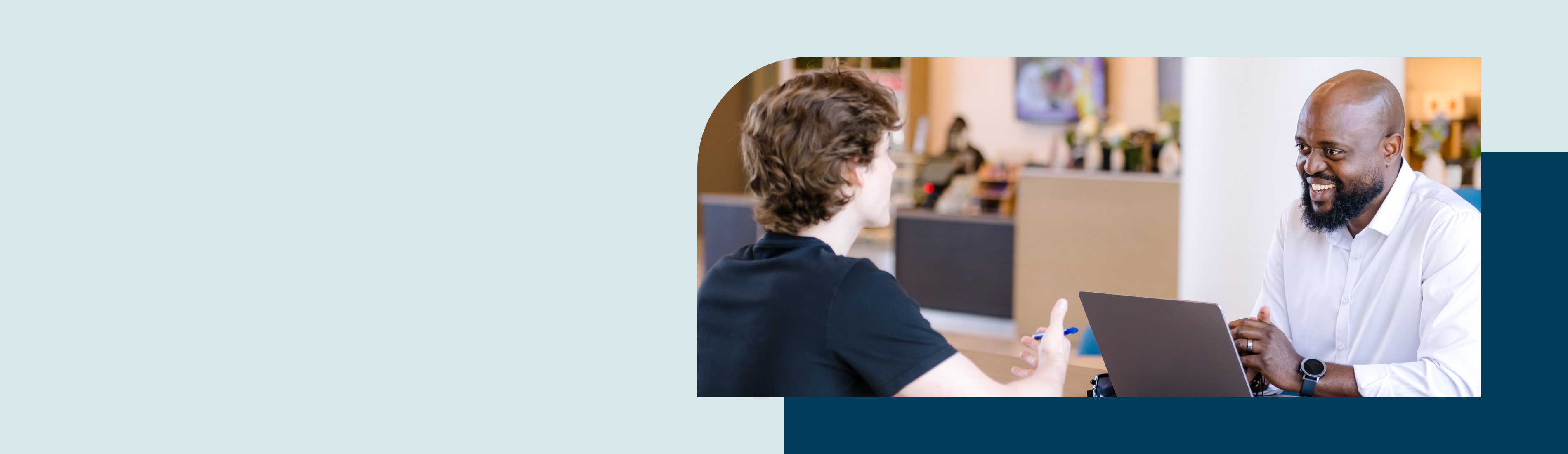 Two people talking while working on a computer