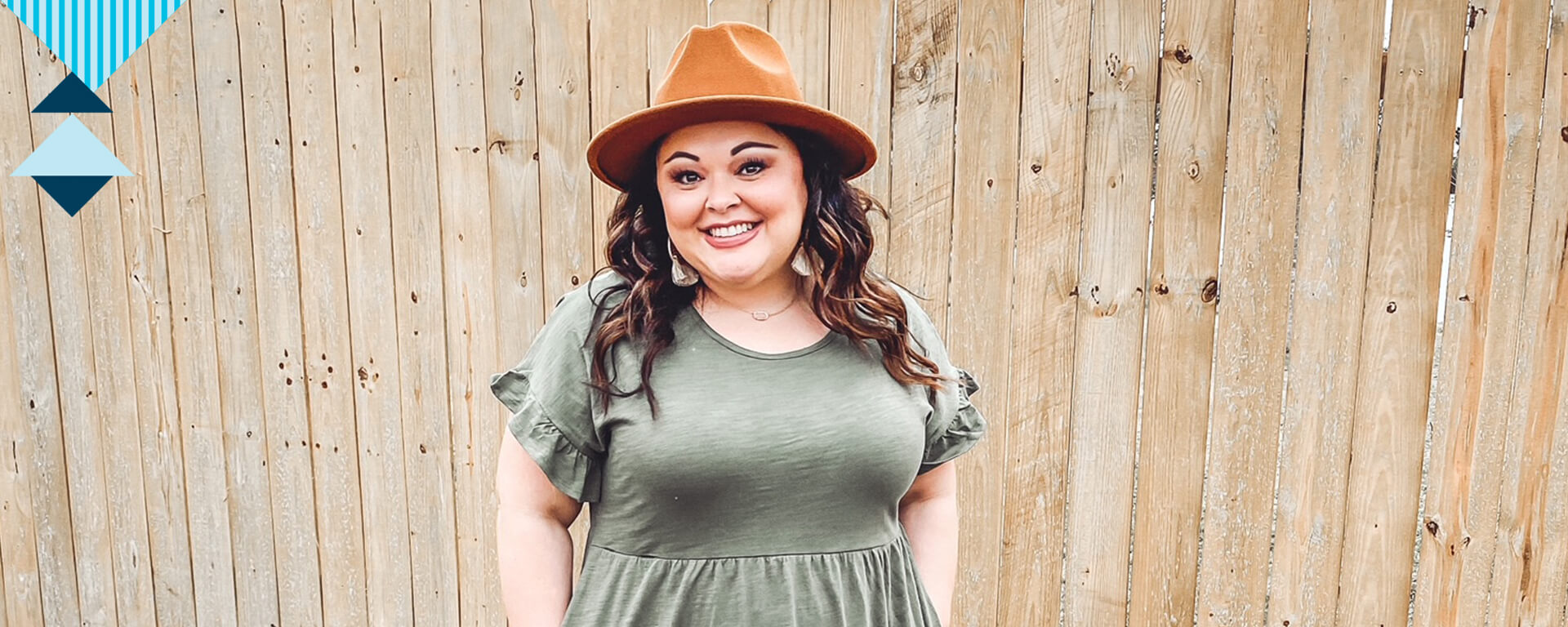 Capital One associate Danika stands outside smiling wearing a dress and a hat standing in front of a wood fence