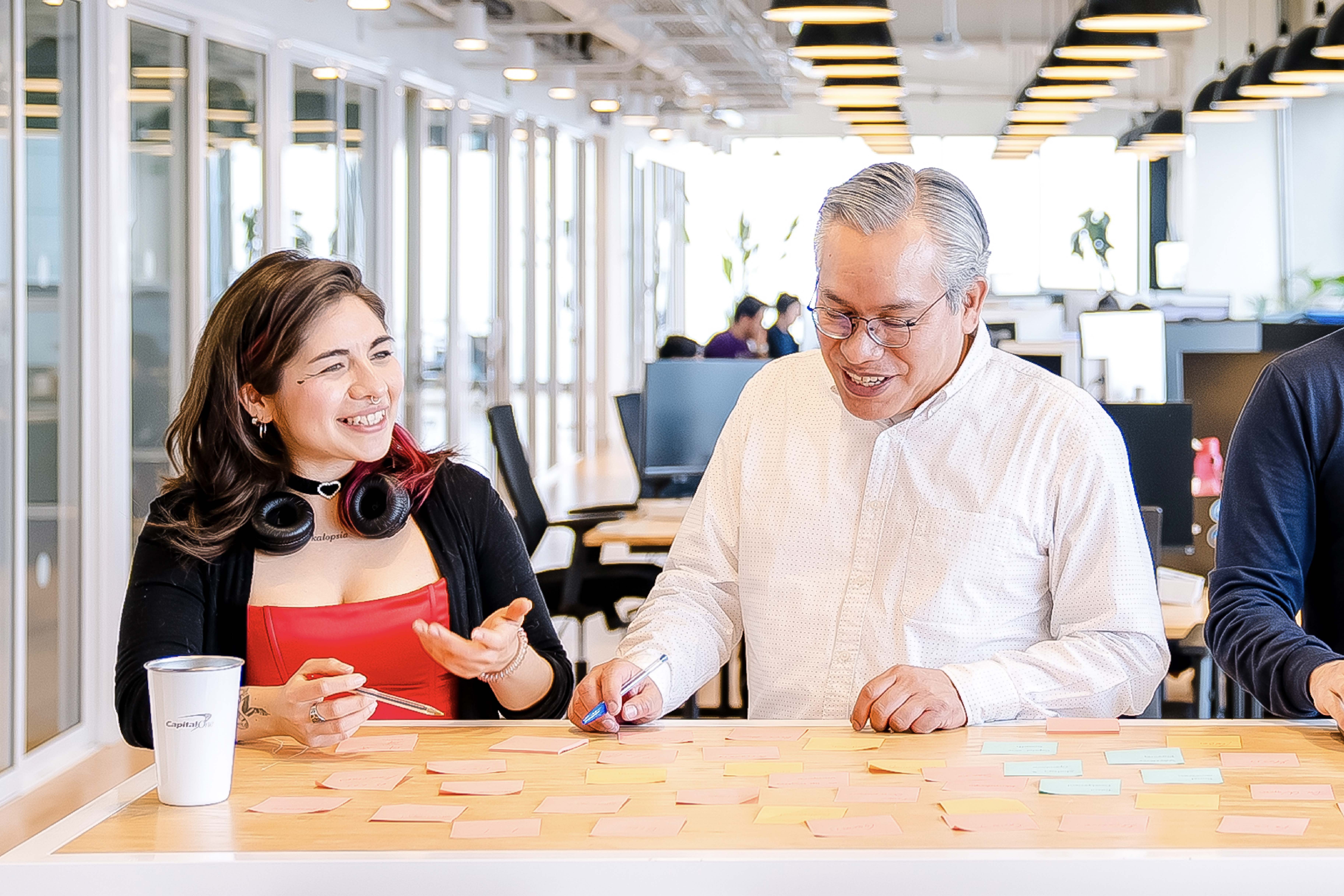 Two Capital One Mexico City associates stand at a table and look at sticky notes together