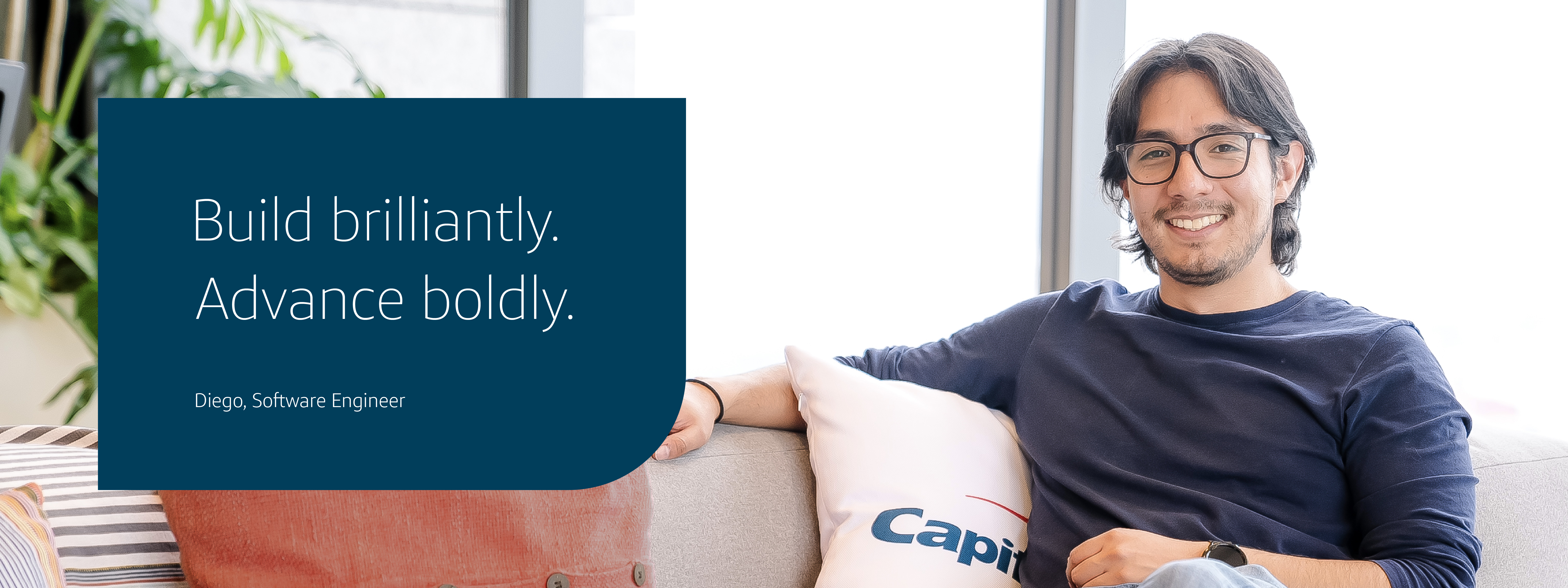 Capital One Mexico City associate Diego sits on a couch wearing a gray shirt and glasses. The image says  "Build brilliantly. Advance boldly." "Diego, Software Engineer"