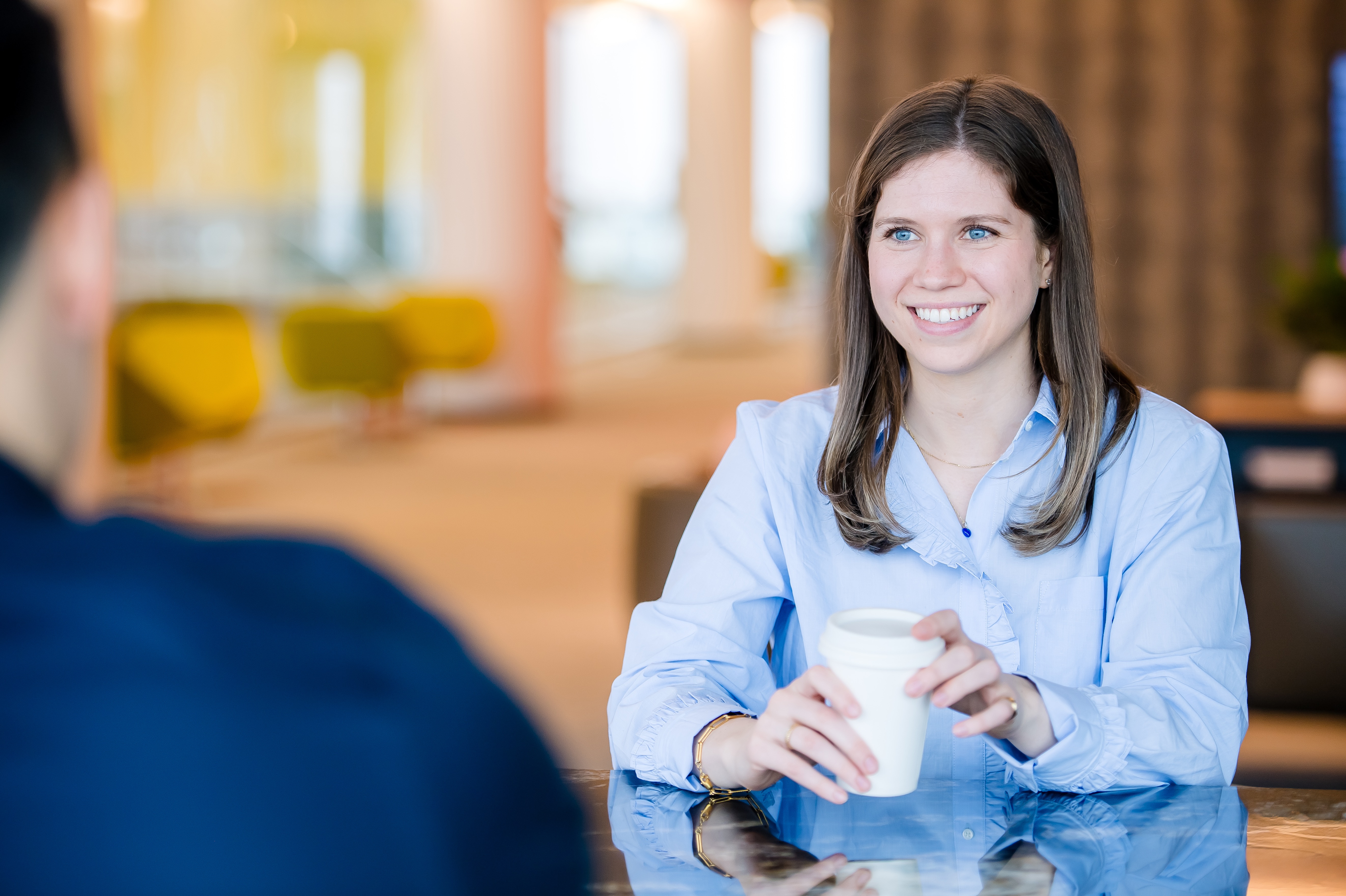 Capital One Strategy Consulting associate sits across the table from her colleague and holds a cup of coffee
