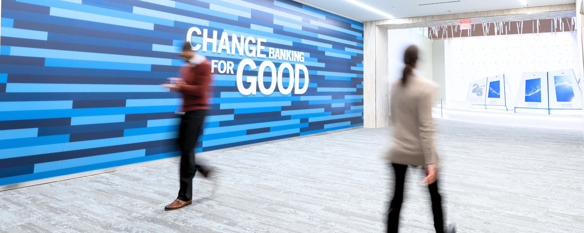 Capital One associate walking past the Change Banking for Good signage on wall