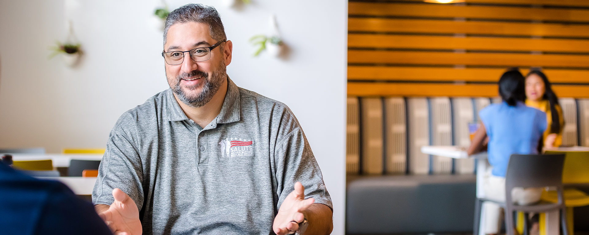 A Capital One associate smiles wearing a gray shirt in the Capital One office