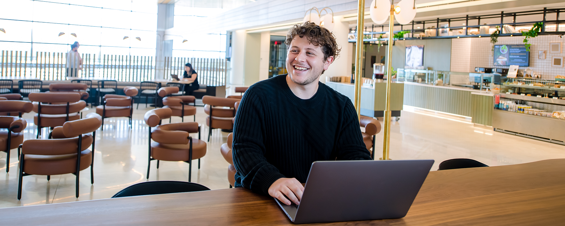 person with laptop on their lap smiling
