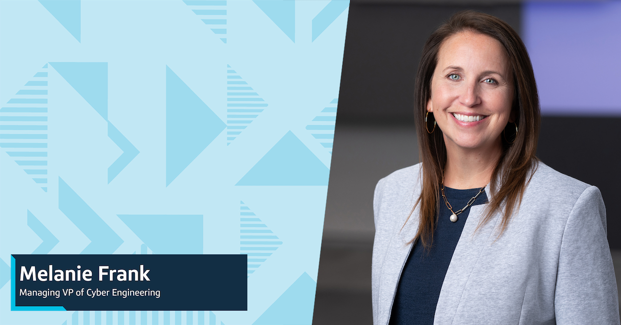 Capital One leader Melanie stands in front of a black background wearing a gray blazer and black blouse.