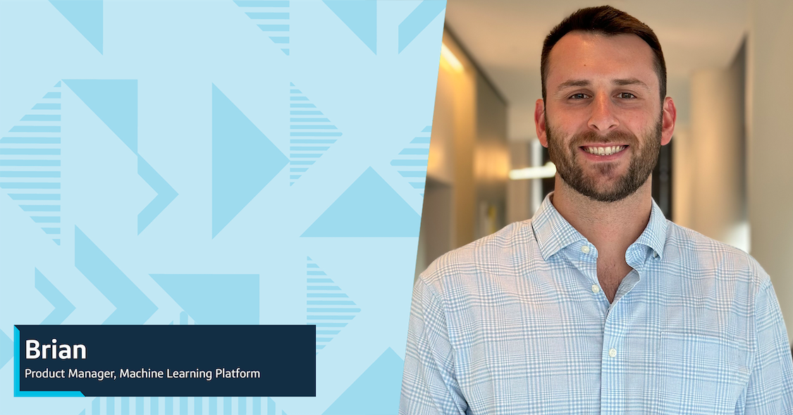 Brian, a Capital One associate, smiles wearing a checked blue shirt in a beige hallway