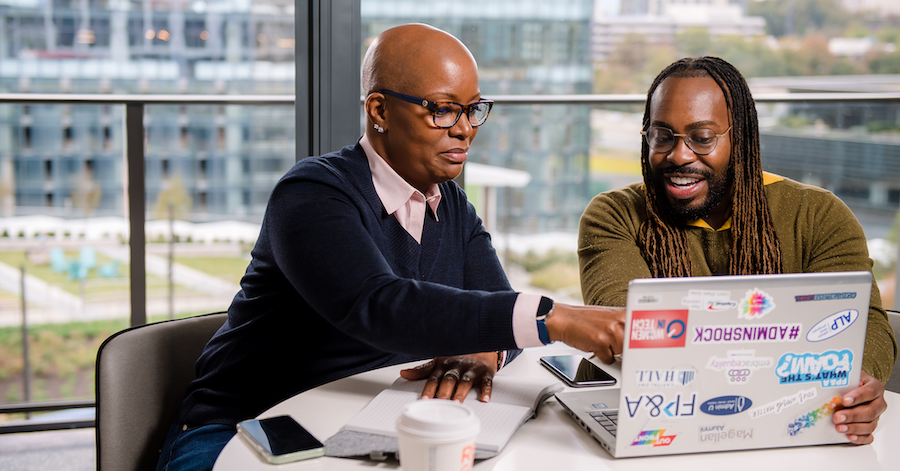 Two Capital One associates sit at a table and look at a laptop