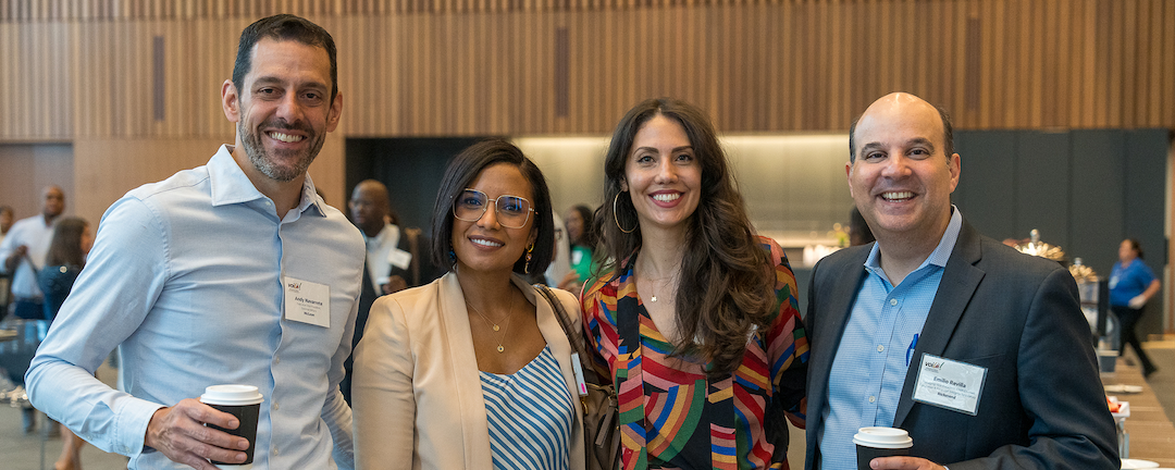 Four Capital One leaders gather in front of a wood background at the VOLIA leadership conference 